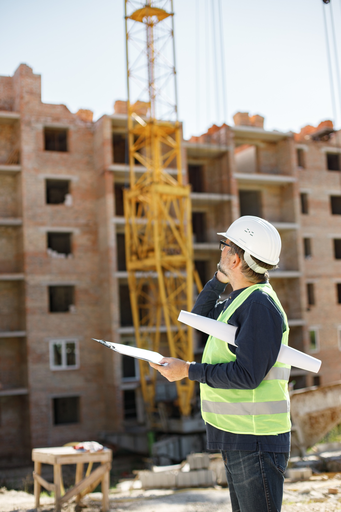 Architect with papers at a construction site talking on the phone